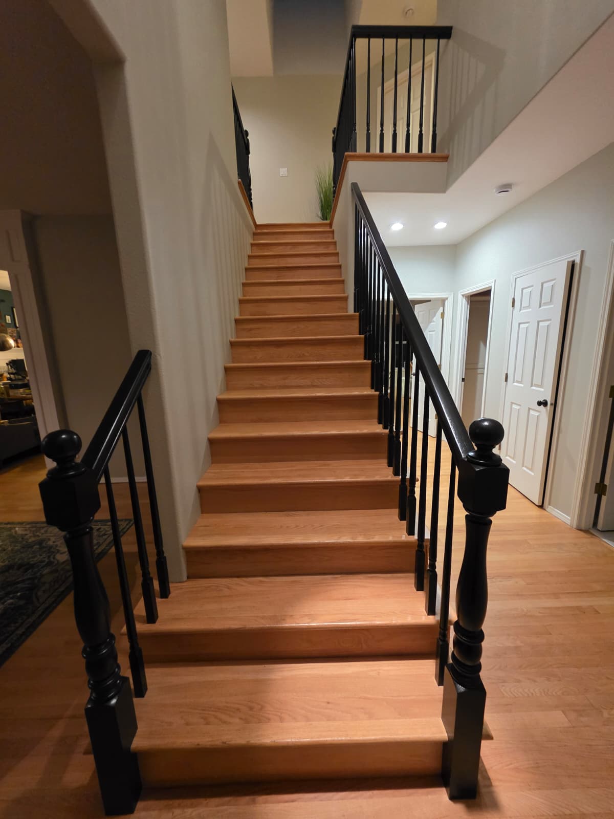 Refinished interior staircase with natural wood treads and freshly painted black railings and newel posts