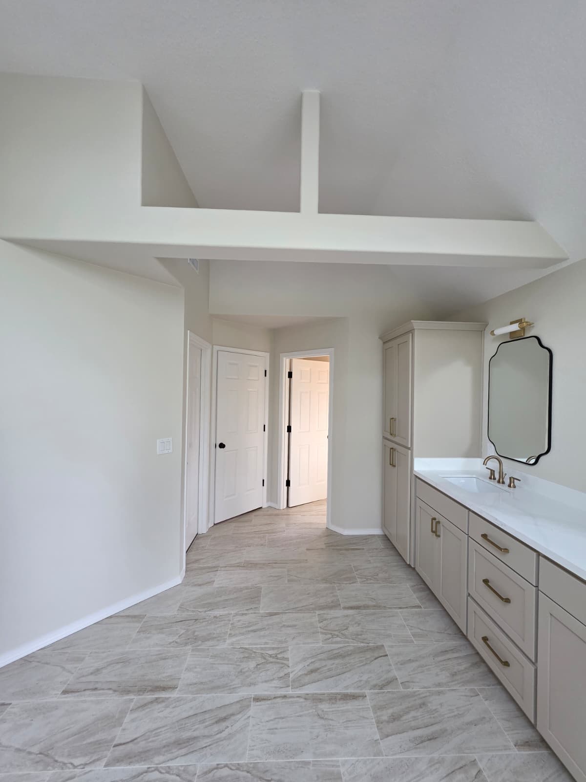 Bright, freshly painted bathroom with vaulted ceiling and warm gray vanity